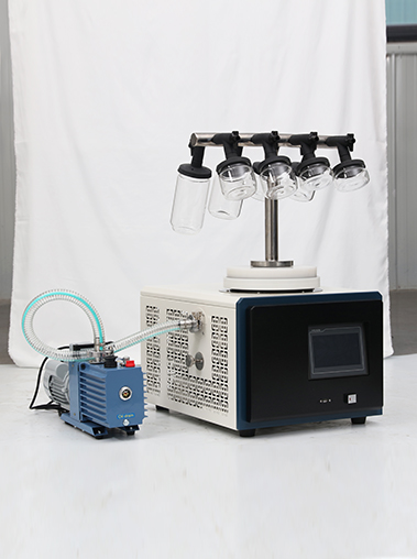 Angled real shot of Geliss laboratory freeze dryer with a T-shaped manifold stand holding wide-mouth glass flasks, connected to a blue rotary vane vacuum pump.